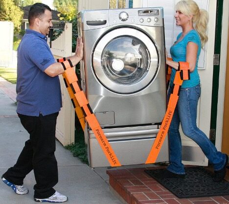 A person and a person carrying a washing machine using forearm moving  straps