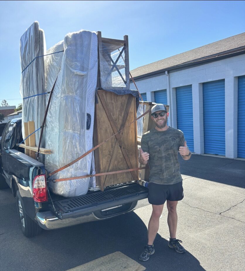 A man standing behind a loaded pickup truck.