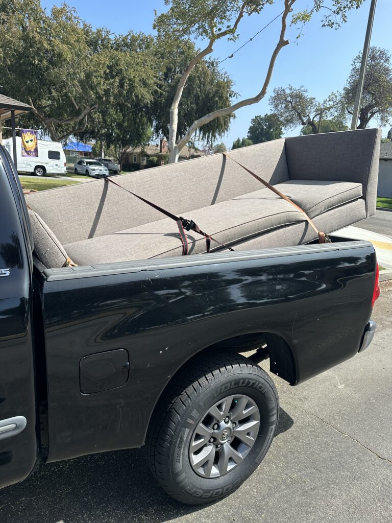 A couch tied down in a pick up truck.