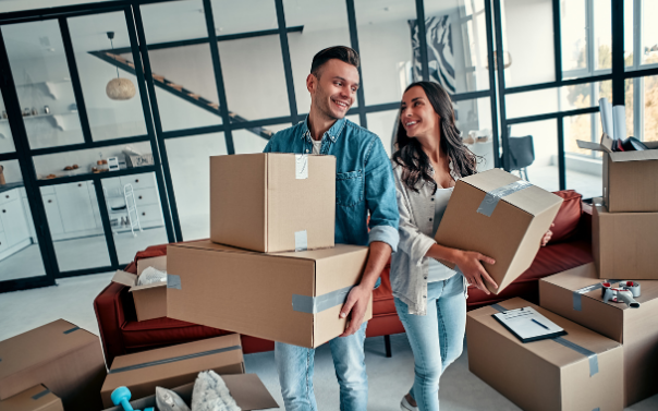 A man and a woman carrying moving boxes