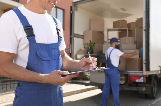 a man making a moving checklist and another man loading a moving truck