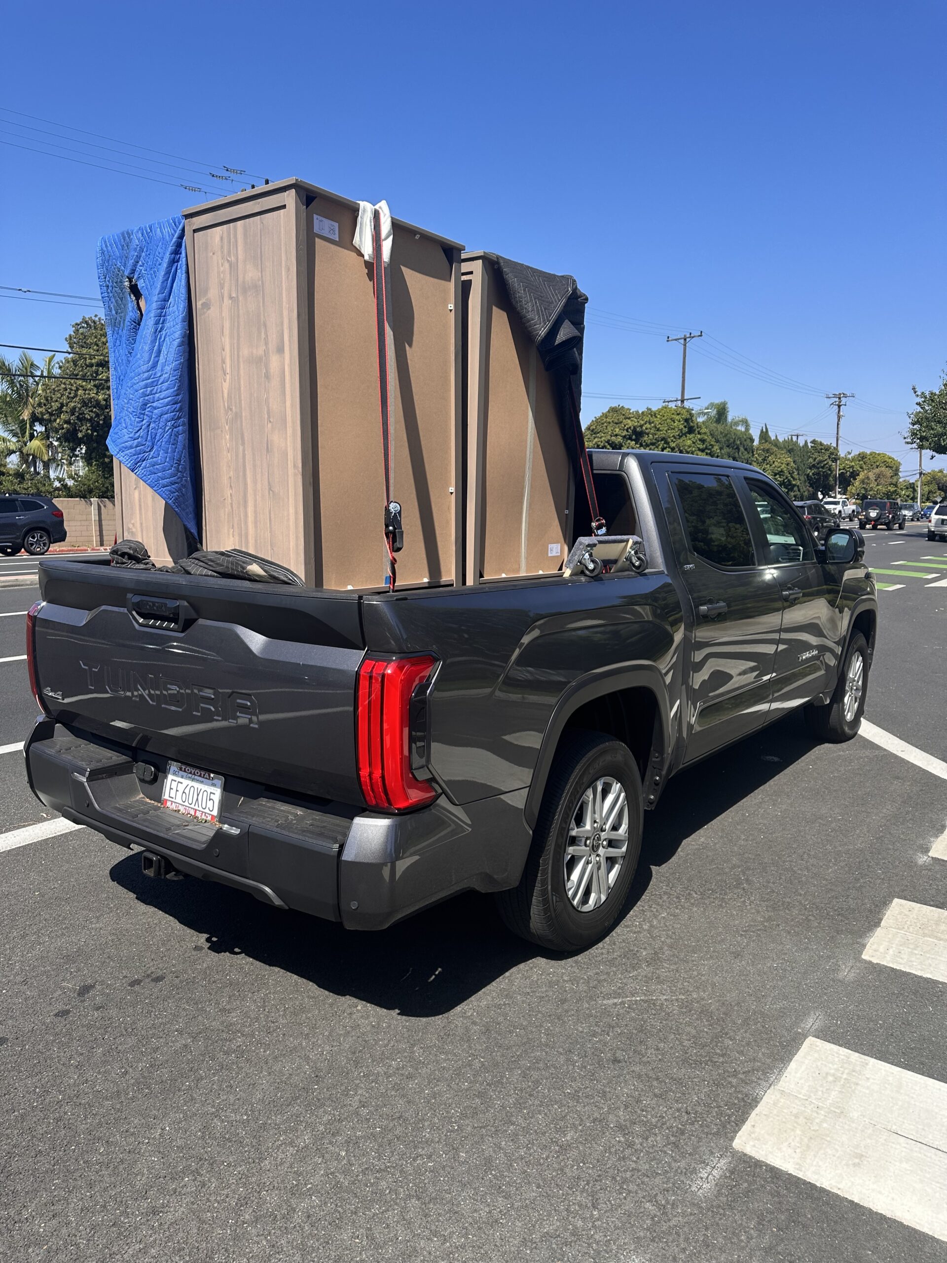 Dark grew 4x4 pickup with large cabinets strapped in the bed for careful delivery.