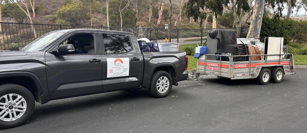 Pickup with attached trailer loaded with furniture and boxes, secured with blankets and straps in Orange County.