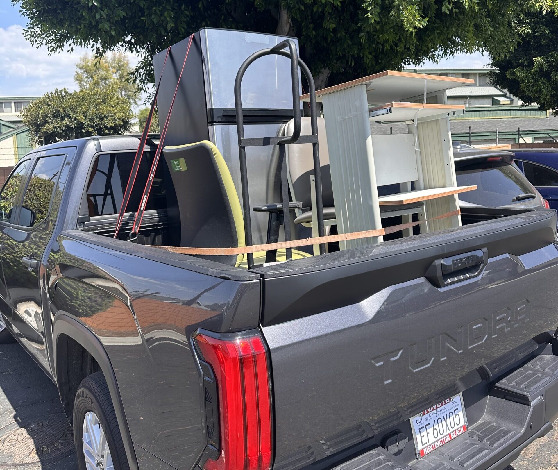 Household items strapped in a pickup truck bed for a dump run haul.